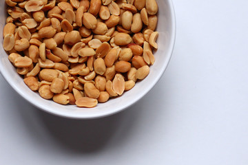 Peanuts in a white bowl on a white background, seen from above