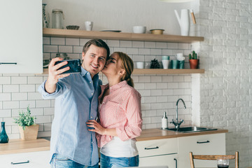 Lovely couple chilling and taking selfie at kitchen