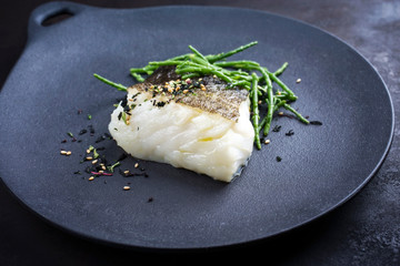 Gourmet fried Japanese skrei cod fish filet with glasswort and furikake as closeup on a modern...