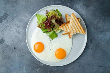 Fried eggs with toast on grey table