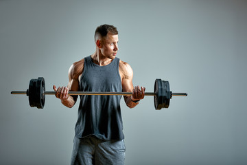 Fototapeta na wymiar Man doing back workout, barbell row in studio over gray background. Copy space