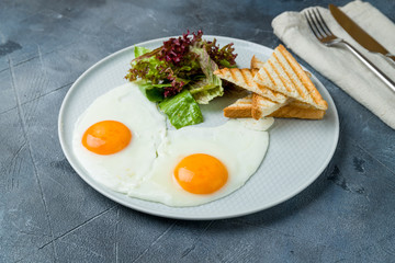 Fried eggs with toast on grey table