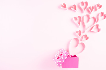 Pink paper hearts splash out from gift box on Light pink pastel paper background. Love and Valentine's day concept.