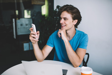 Happy millennial hipster guy checking smartphone notification for application during online...