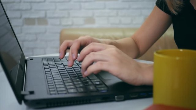 Young woman typing on laptop keyboard in the home. Close up girl hands writing on laptop computer keyboard. Woman's hands pressing keys on a laptop keyboard trying to access data.