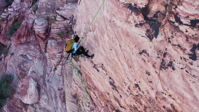 Female rock climber rappels and untangles rope during abseil at Red Rock Canyon