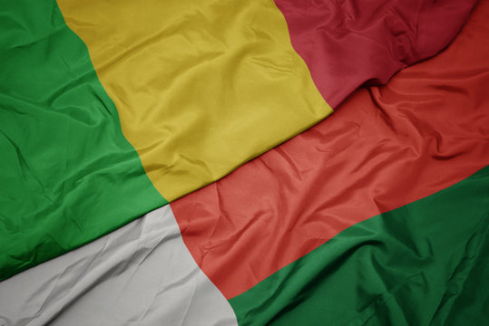 waving colorful flag of madagascar and national flag of mali.
