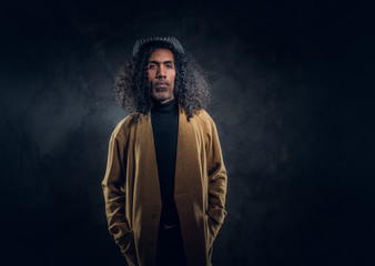 Portrait of middle aged charismatic man in brown coat at dark photo studio.