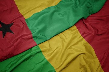 waving colorful flag of mali and national flag of guinea bissau.