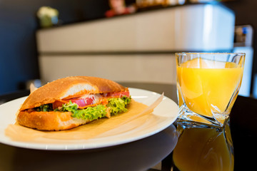 Close up hot dog sandwich on plate and glass of orange juice
