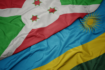 waving colorful flag of rwanda and national flag of burundi .