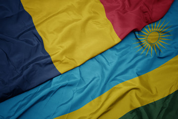 waving colorful flag of rwanda and national flag of chad.
