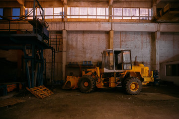 Fototapeta na wymiar Old rusty tractor in abandoned factory warehouse