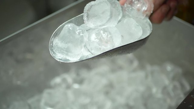 Male hand takes pieces of clean ice cubes to make drinks at bar counter