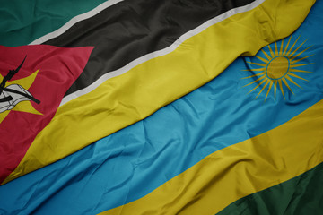 waving colorful flag of rwanda and national flag of mozambique.