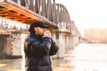 portrait of young rapper posing under a metal bridge