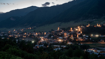 Night view on Mestia with its beautiful illuminated Svan Towers and high mountains. Svaneti, Georgia.