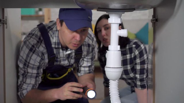 Housewife shows plumbing leak under sink