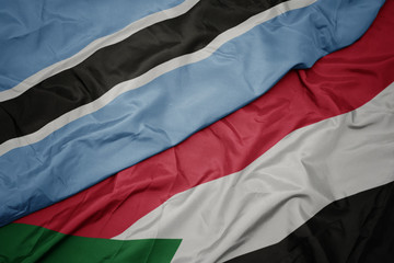waving colorful flag of sudan and national flag of botswana.