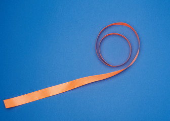 orange silk thin ribbon twisted on a blue background