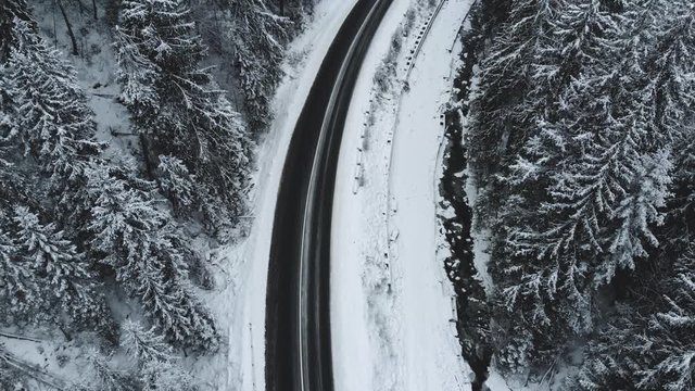 Winter mountain road surrounded by snowy trees, aerial view.