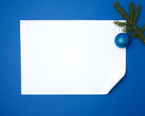 white blank sheet of paper with a curled bottom corner and a green sprig of spruce