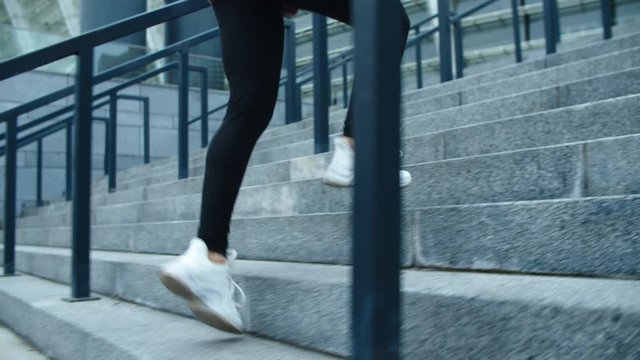 Close up fitness woman climbing up stairs. Woman jogger finishing run exercise