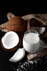 fresh coconut milk in a glass against a dark background, coconut cosmetic cream, milkshake with coconut slices