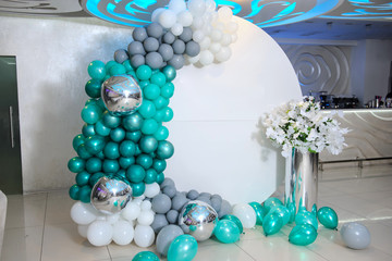 close up photo of a white round photo zone with turquoise and gray baloons at a boy's birthday party in a restaurant