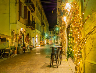 Christmas lights illuminate the deserted streets of the historic center of Como in the night