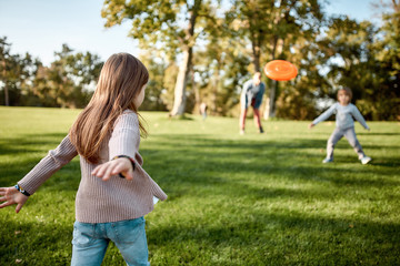 Obraz premium Here we go again. Little girl playing frisbee with her family in the park on a sunny day
