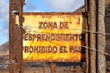 A rusty warning sign in Spanish: zona de desprendimiento prohibido el paso (English: entry...