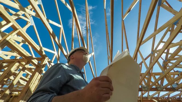 Construction worker on site with building plans, low angle view