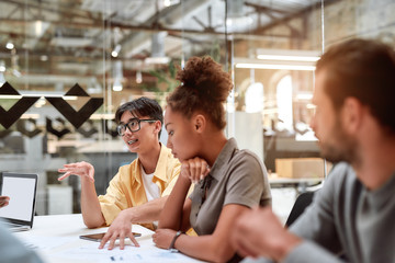 Multicultural team. Group of young business people discussing something with his young colleagues while working together in the modern office