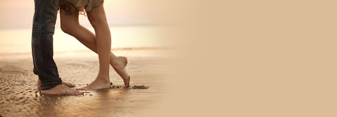 A loving young couple hugging and kissing on the beach. Lovers man and woman barefoot in the wet...