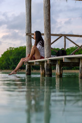 Fototapeta premium Beautiful woman sitting on a dock in a beautiful lake in the morning