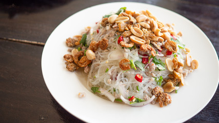 Glass Noodle,Pork,Nut Spicy Salad (Yum Woon Sen)  Full of fried beans and dried shrimp in White plate.