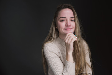 Portrait of a beautiful, sweet, young girl on a gray background in a beige sweater
