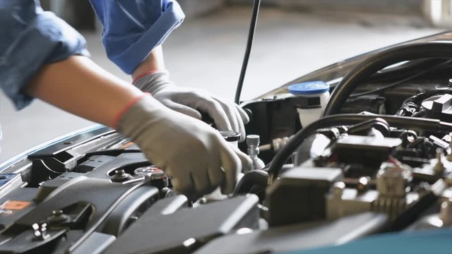 Asian Man mechanic inspection writing note on clipboard.Blue car for service maintenance insurance with car engine.for transport automobile automotive 