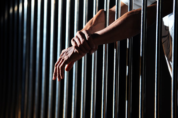 close up of prisoner hands in jail background