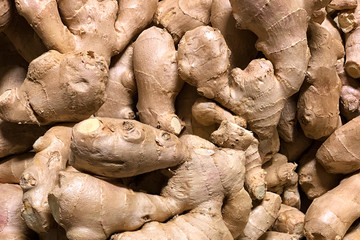 Background texture of a pile of dry golden ginger roots piled in one big pile on a greengrocery counter