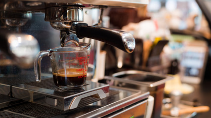 Coffee in measuring cup on a coffee machine