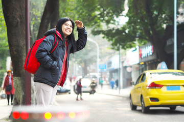 Asian tourist woman standing on pavement and waiting for bus or taxi