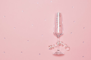 Festive background with an empty glass of champagne, streamers and sequins.