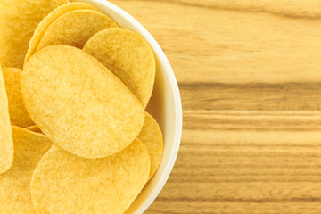 potato chips on bowl on wooden background.