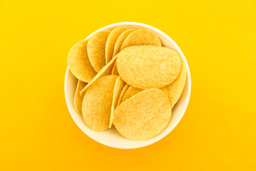 potato chips on bowl on yellow background.