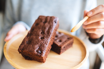 Closeup image of a woman eating delicious brownie cake with spoon