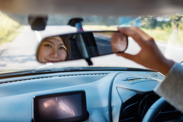 A woman adjusting a rear view mirror while driving car