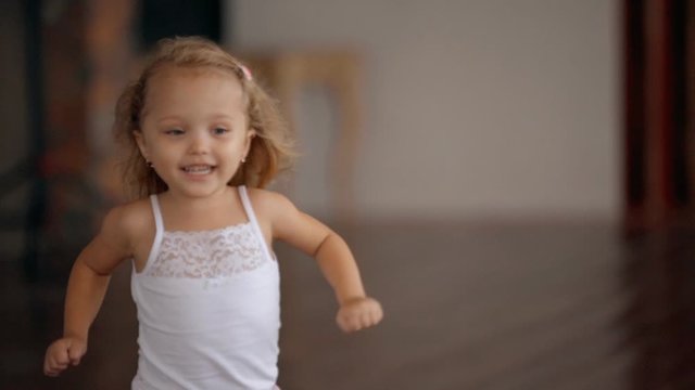 happy little girl running through house with stylish modern interior in slow motion. kid in pajamas running towards mother's hands. concept of carefree childhood. lifestyle time spending of a child