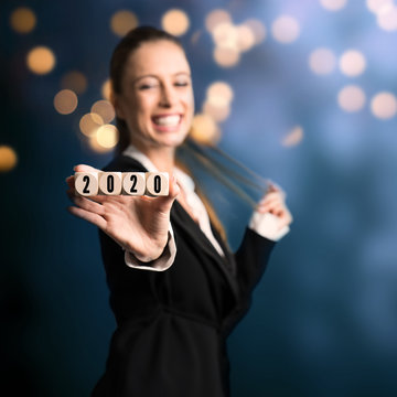 young woman with cubes and message 2020 in front of colorful lights background